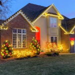 Holiday lights in white gold and red on a house in landscaping at dusk - Class Act Glass Best Window Cleaning Services in Mankato and Southern Minnesota
